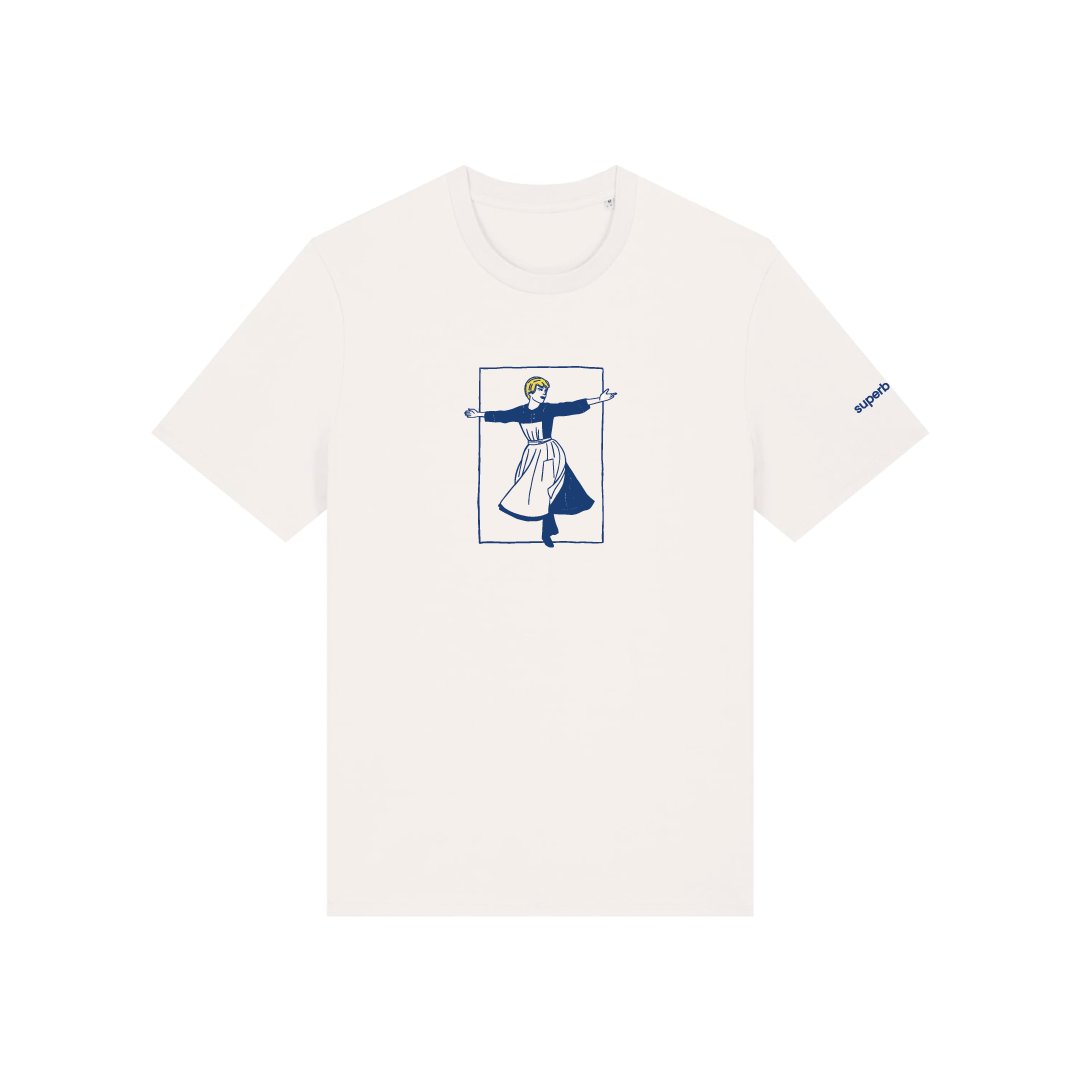 Camiseta blanca de manga corta con ilustración frontal inspirada en The Sound of Music, con Maria de brazos abiertos en azul, blanco y amarillo, y pequeño logotipo azul en la manga.