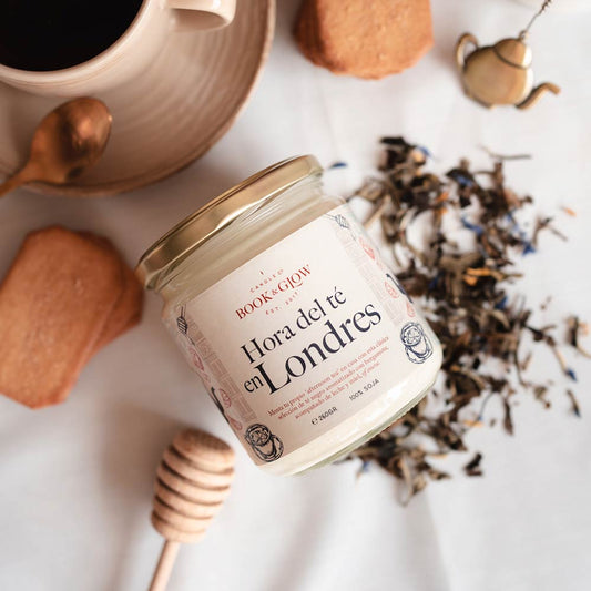 Vela de Book and Glow Hora del té en Londres, presentada en recipiente de cristal, etiqueta blanca con título en color negro sobre mesa con té negro y miel.