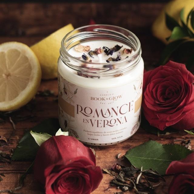 Vela de Book and Glow Romance en Verona presentada en recipiente de cristal con pétalos de rosas y etiqueta blanca y título en beige.