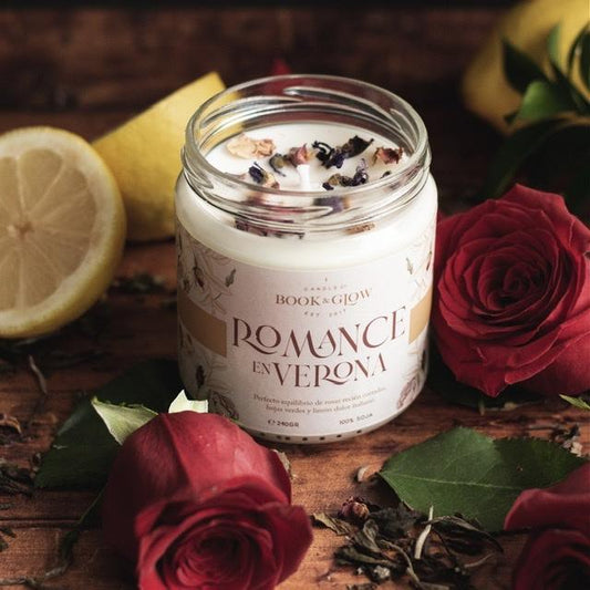 Vela de Book and Glow Romance en Verona presentada en recipiente de cristal con pétalos de rosas y etiqueta blanca y título en beige.