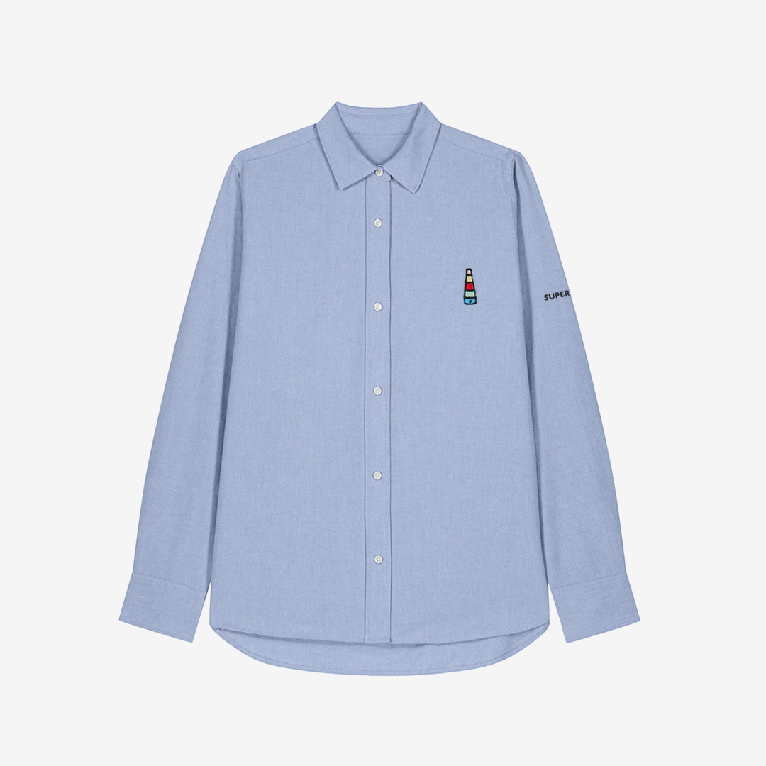 Camisa celeste de mujer con botones blancos y bordado pequeño de logo de incensario conmemorativo del cartel del Orgullo de Sevilla en pecho izquierdo.