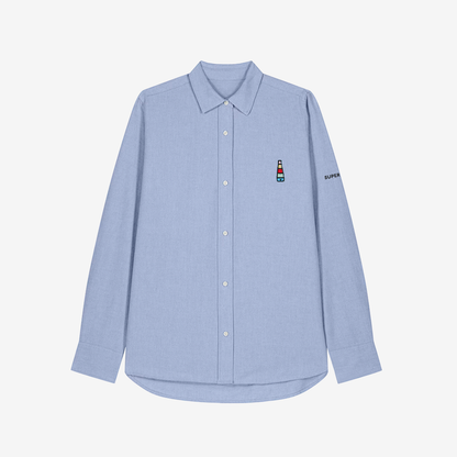 Camisa celeste de mujer con botones blancos y bordado pequeño de logo de incensario conmemorativo del cartel del Orgullo de Sevilla en pecho izquierdo.