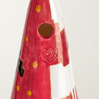 Detalle del capirote cerámico inspirado en el icónico sweater rojo de ovejas, lleno de simbolismo, que Diana lució pocos meses después de anunciar su compromiso con el entonces príncipe Carlos de Inglaterra.