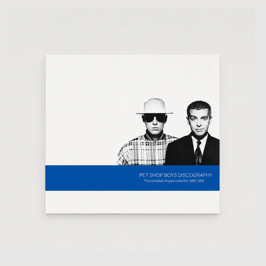 Portada del álbum Discography: The Complete Singles Collection 1985–1991 de Pet Shop Boys con una fotografía en blanco y negro de Neil Tennant y Chris Lowe sobre fondo blanco y una banda azul en la parte inferior con el título del recopilatorio.