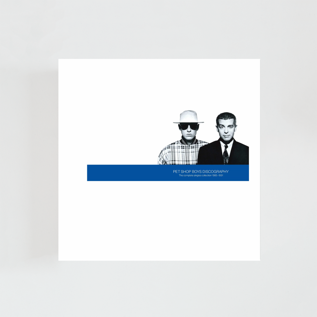 Portada del álbum Discography: The Complete Singles Collection 1985–1991 de Pet Shop Boys con una fotografía en blanco y negro de Neil Tennant y Chris Lowe sobre fondo blanco y una banda azul en la parte inferior con el título del recopilatorio.