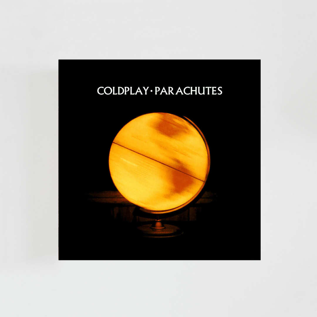 Portada del álbum Parachutes de Coldplay: fondo negro completamente oscuro con una imagen central en forma de fotografía esférica de la Tierra vista desde el espacio, iluminada de manera tenue y cálida. El planeta aparece pequeño y ligeramente desenfocado, con tonos amarillos y anaranjados suaves que contrastan con el negro profundo del fondo. La composición es minimalista, con mucho espacio vacío alrededor, transmitiendo sensación de aislamiento, calma y melancolía.