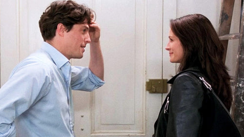 Escena de la película Notting Hill en la que se observa a William (Hugh Grant) y Ana Scott (Julia Roberts) hablando tras una puerta blanca.