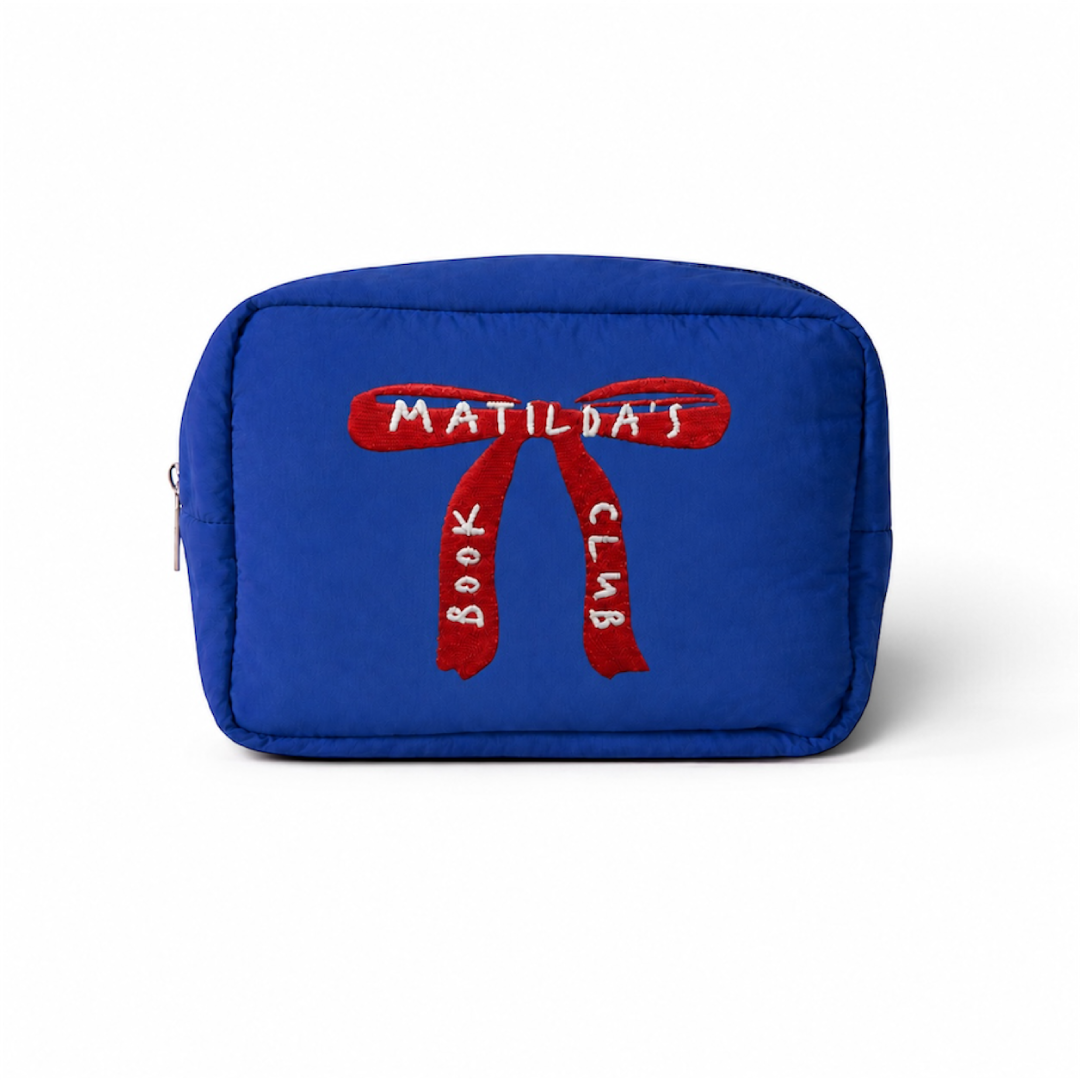 Estuche acolchado azul de Matilda’s Book Club sobre fondo blanco, con un gran lazo rojo bordado y el nombre de la colección en hilo blanco.