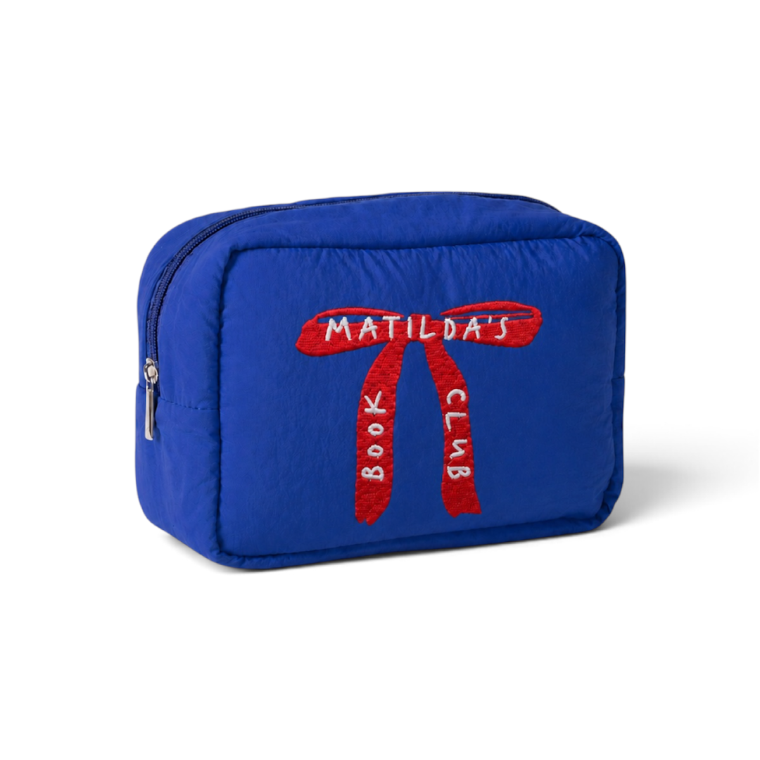 Estuche acolchado azul de Matilda’s Book Club visto en perspectiva, con lazo rojo bordado en el frontal y cremallera metálica en el lateral.