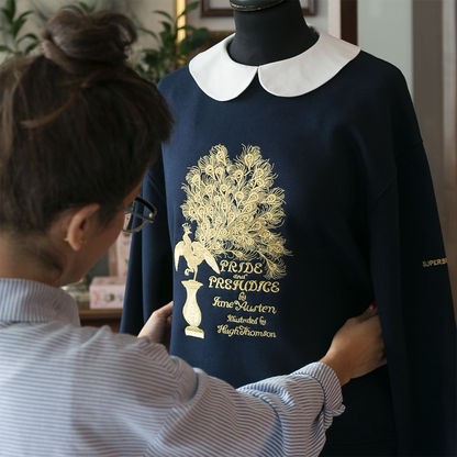 Sudadera color azul marino con bordado en dorado de la primera edición de la portada Pride and Prejudice de Jane Austen sobre maniquí.