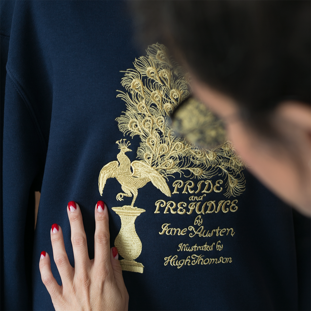 Detalle de la sudadera color azul marino con bordado en dorado de la primera edición de la portada Pride and Prejudice de Jane Austen.