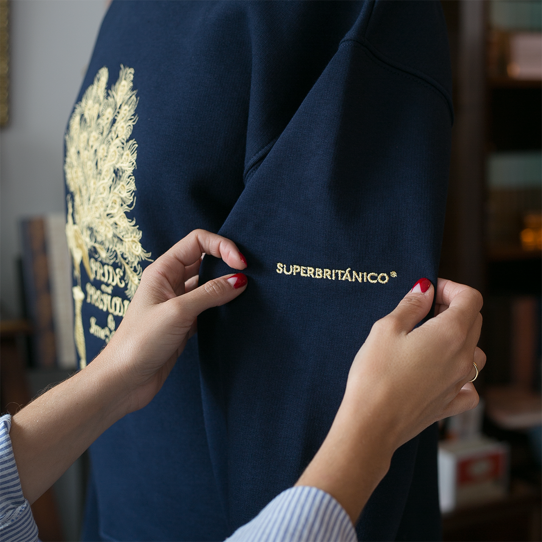 Detalle del logo de Superbritánico de la sudadera color azul marino con bordado en dorado de la primera edición de la portada Pride and Prejudice de Jane Austen.