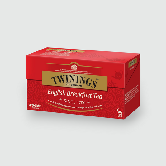 Caja de té Twinings of London English Breakfast (25 bolsitas) en su empaque rojo distintivo, mostrada en ángulo oblicuo sobre un fondo gris claro neutro.