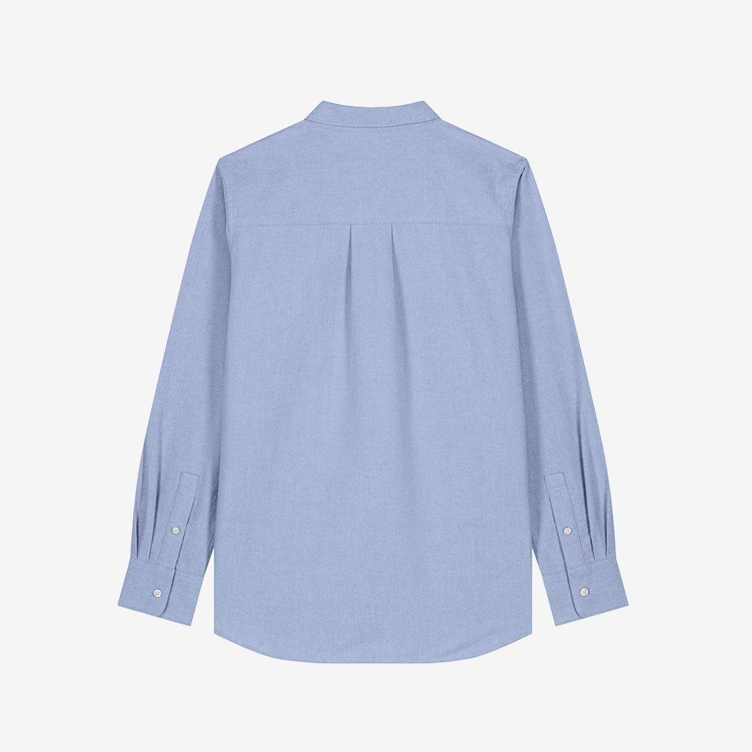 Parte trasera de camisa clásica de color celeste y corte de mujer sobre fondo blanco.