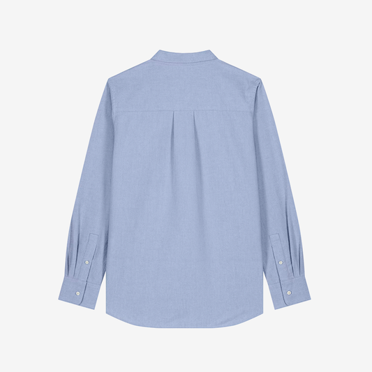 Parte trasera de camisa clásica de color celeste y corte de mujer sobre fondo blanco.