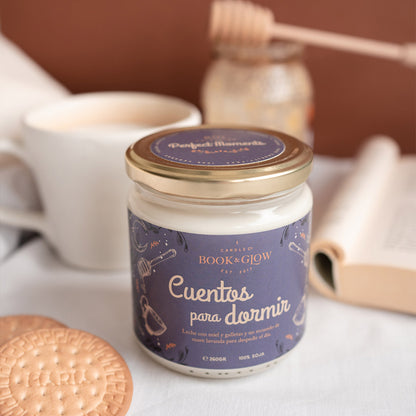 Vela de Book and Glow Cuentos para dormir presentada en recipiente de cristal cerrado, etiqueta azul con título en blanco sobre mesa.