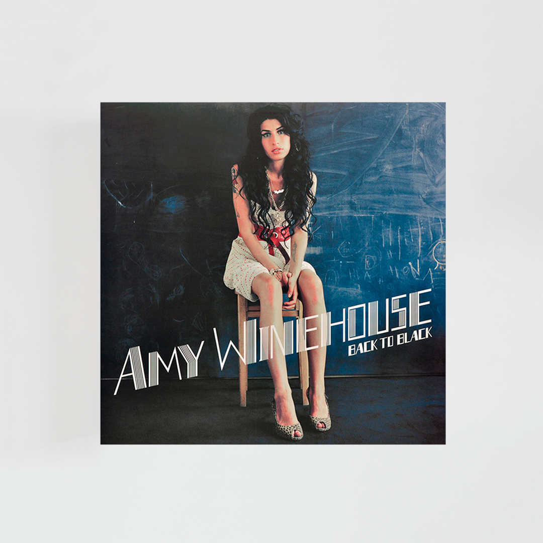 Portada del vinilo Back to Black de Amy Winehouse, álbum de soul británico con la cantante sentada frente a un fondo azul oscuro, vestida de blanco y con su icónico peinado.