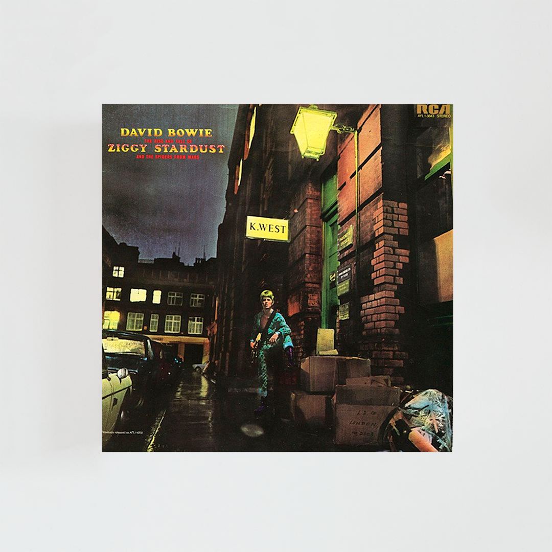 Portada del vinilo The Rise and Fall of Ziggy Stardust and the Spiders from Mars de David Bowie, con el cantante vestido como Ziggy Stardust en un callejón iluminado, álbum icónico de glam rock británico de 1972.